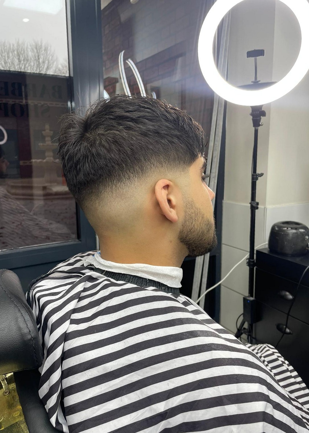 Verse skin fade met baard, van opzij gezien, in de kappersstoel